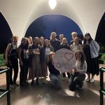 OPIRG volunteers gathered under a gazebo with a round white sign that reads "I love OPIRG"